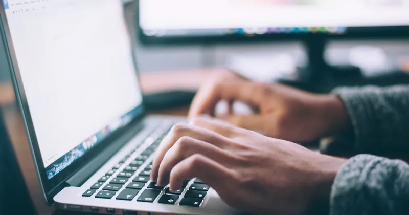 Person working on a laptop while taking a customer support call