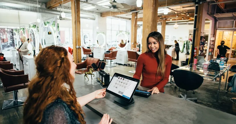 Shopify merchant on a phone call while a laptop shows the storefront