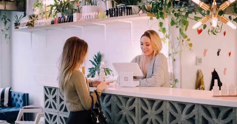 Shopify merchant at a retail counter with a laptop chat widget and a store phone